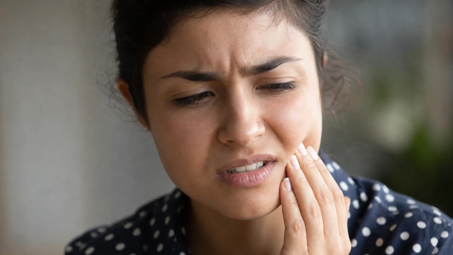 Personne se touchant la joue avec une expression gênée, gros plan sur le bas du visage