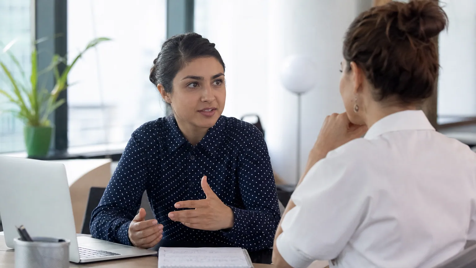 Une femme échange avec une conseillère lors d'un entretien de bilan de compétences dans un bureau lumineux