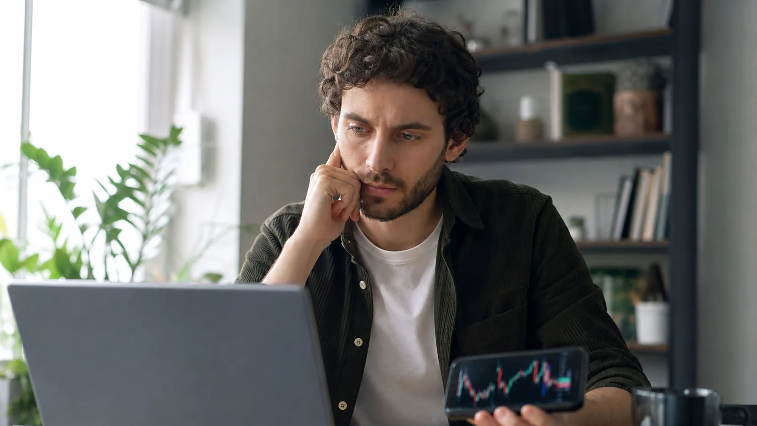 Une personne analyse des graphiques financiers sur son ordinateur portable à son bureau