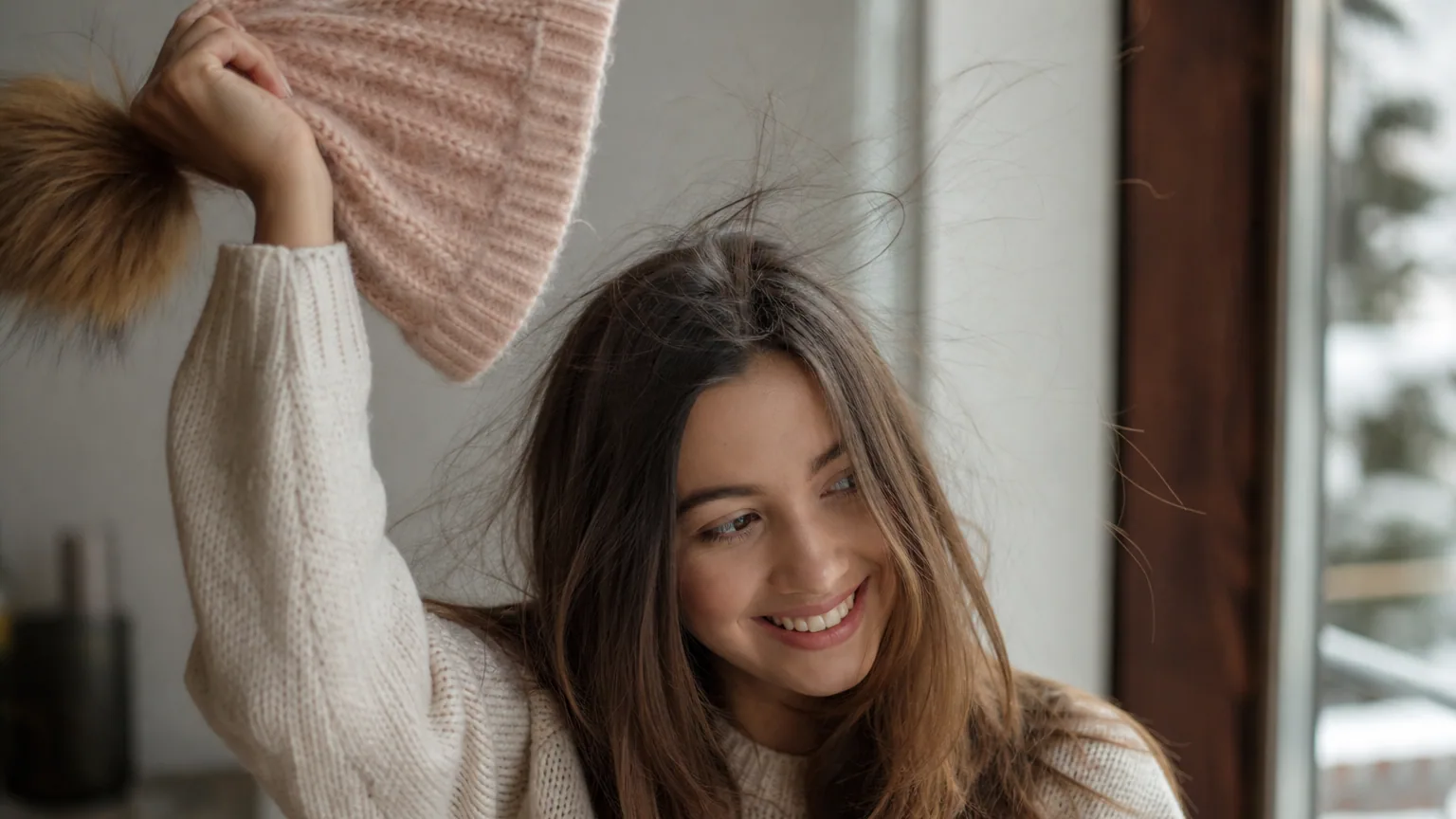 Femme retirant son bonnet de laine en hiver, quelques cheveux soulevés par l'électricité statique