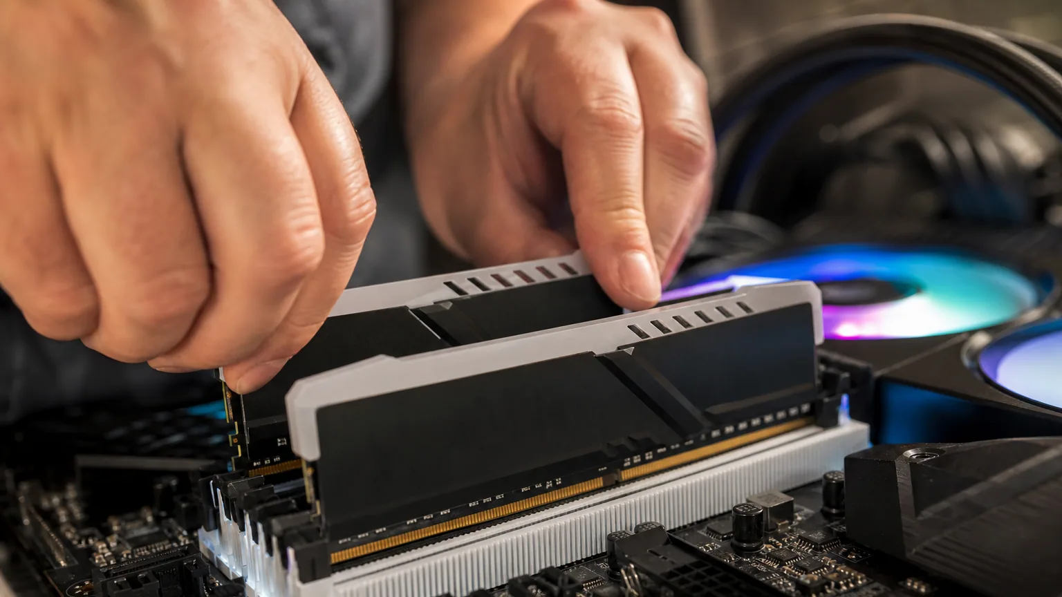 Mains installant deux barrettes de mémoire vive dans une carte mère de PC de bureau
