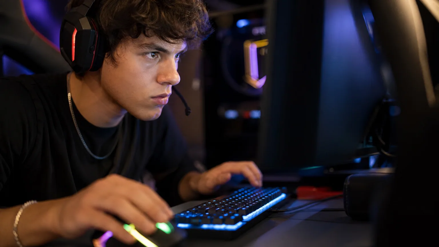 Jeune joueur concentré avec un casque devant son écran lors d'une session d'entraînement compétitif