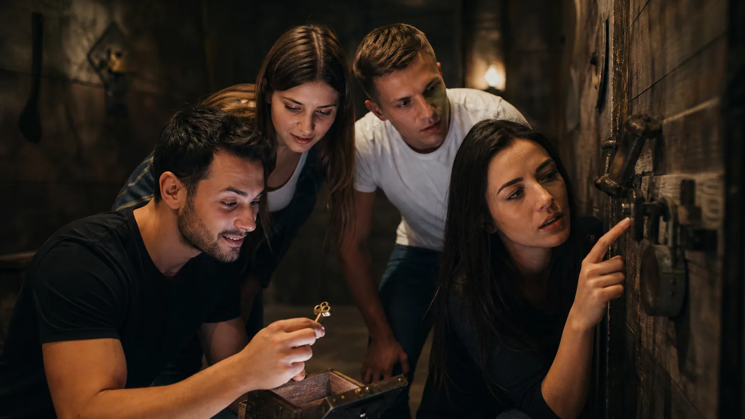 Quatre joueurs concentrés fouillent une salle d'escape game à la recherche d'indices