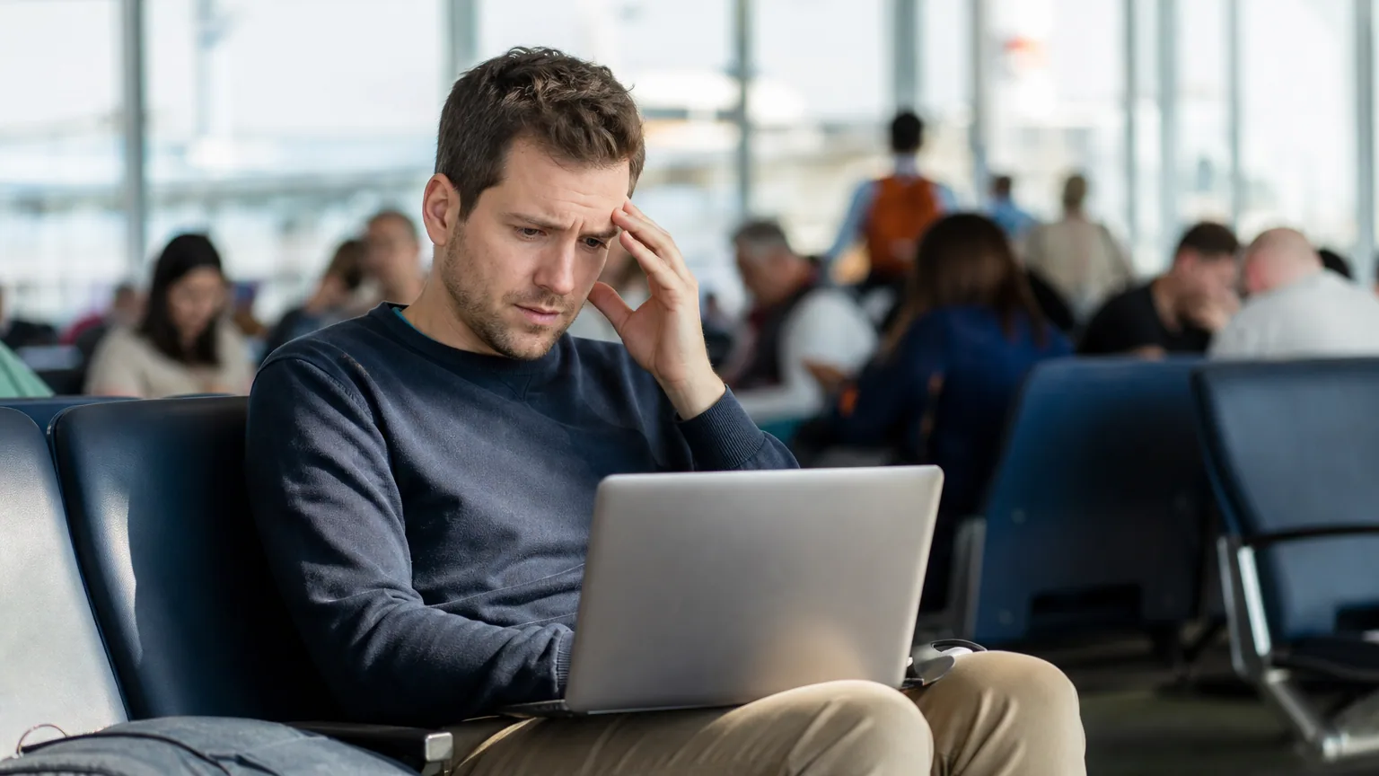 Un voyageur connecte son ordinateur portable à un réseau Wi-Fi public dans un hall d'aéroport