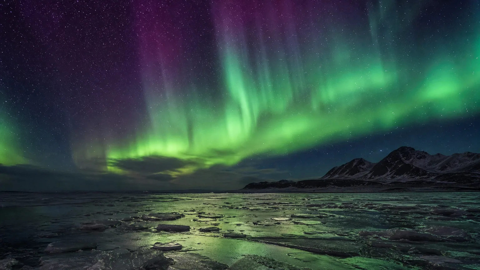Aurore boréale verte et violette illuminant un ciel nocturne au-dessus d'un paysage glacé