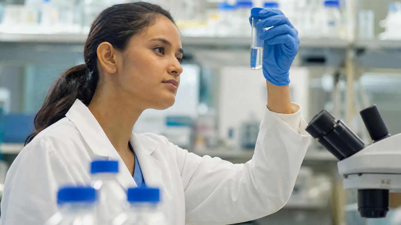 Une chercheuse en blouse blanche examine un flacon dans un laboratoire de recherche médicale