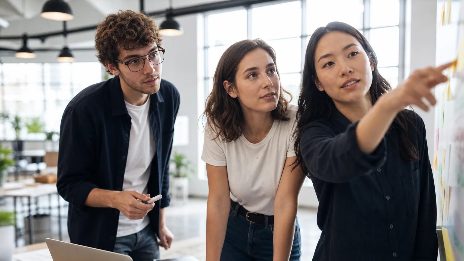 Trois fondateurs de startup discutent autour d'un ordinateur portable dans un bureau lumineux