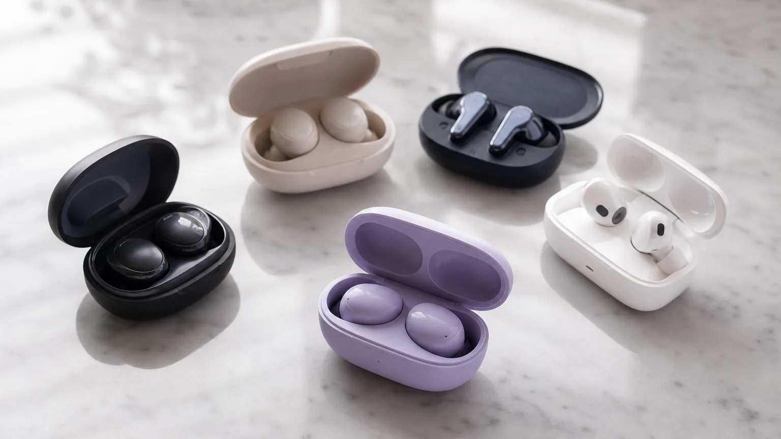 Plusieurs paires d'écouteurs true wireless posées dans leurs boîtiers sur une surface claire