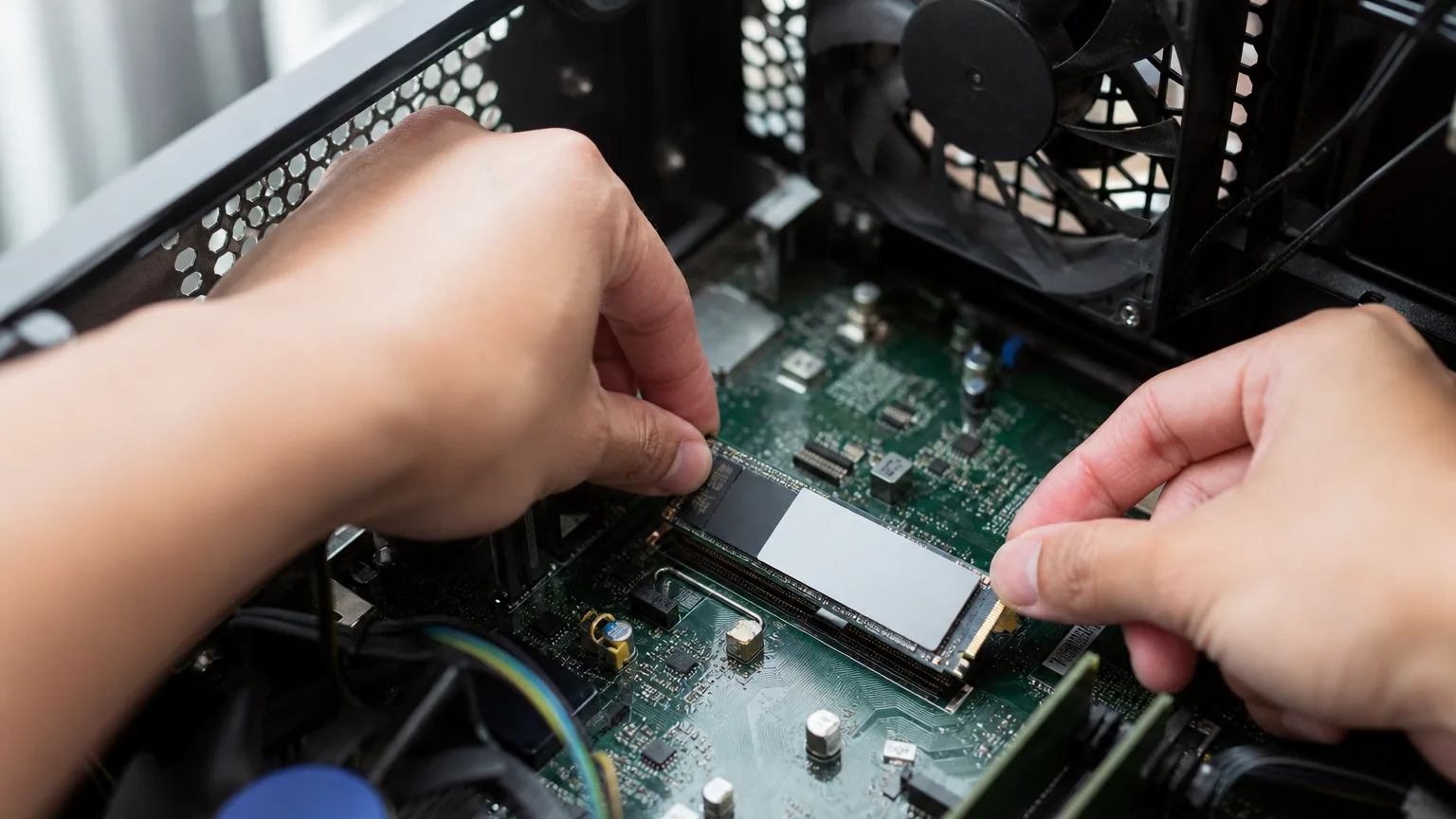 Mains installant un SSD M.2 NVMe sur la carte mère d'un ordinateur ouvert