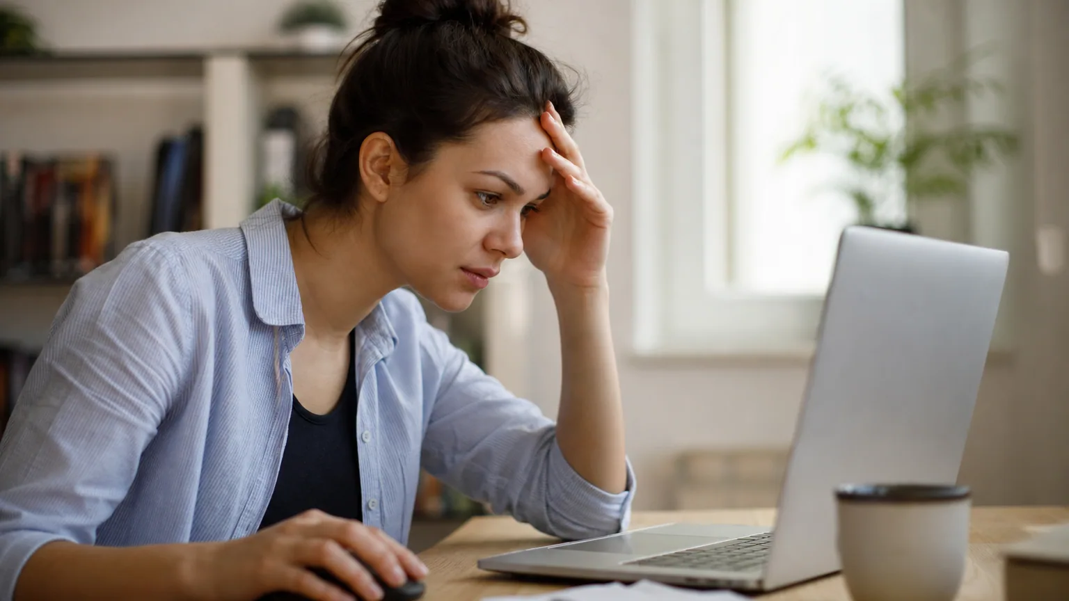 Une personne concentrée devant son ordinateur portable tentant de récupérer un fichier supprimé