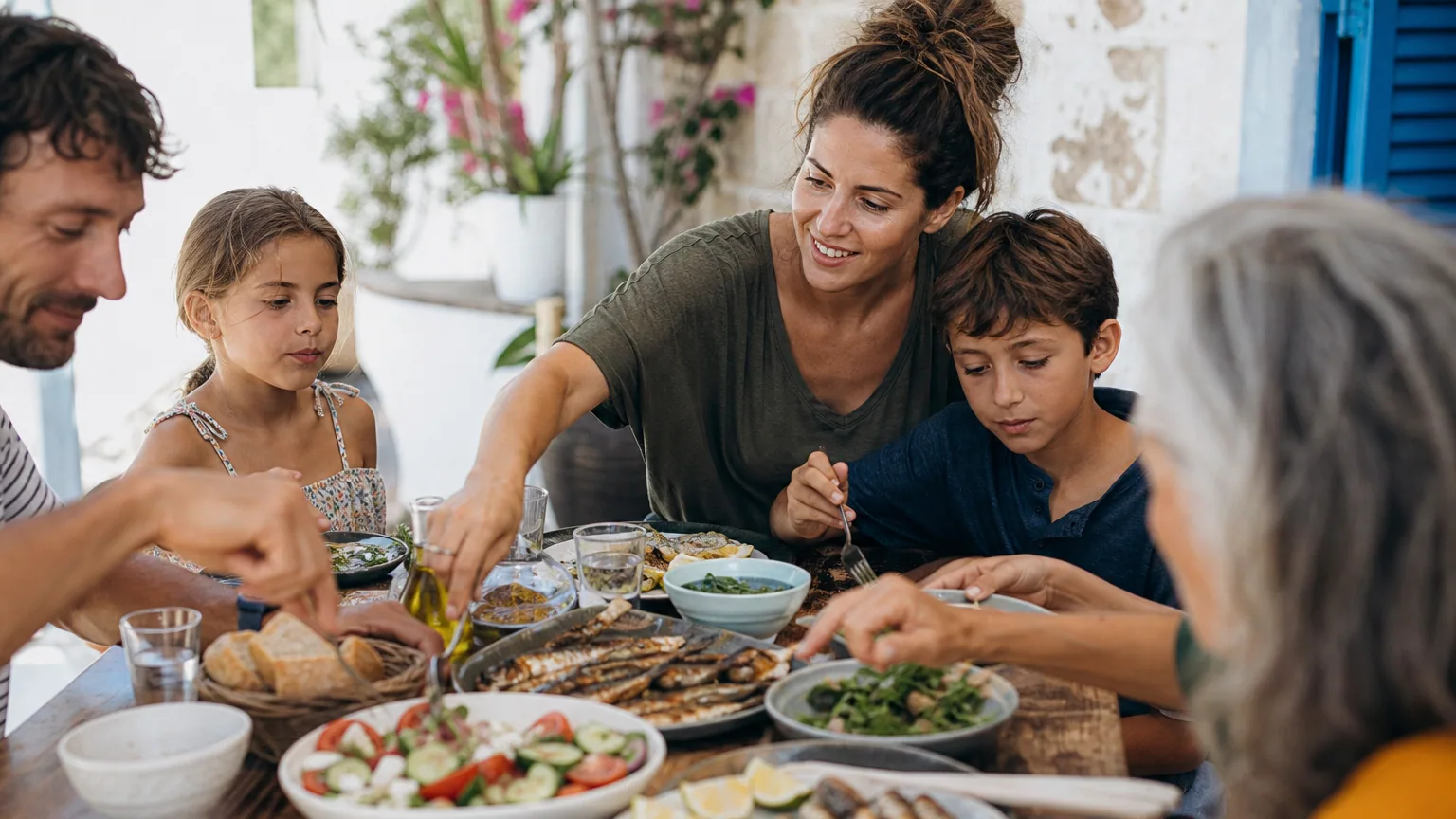 Table conviviale garnie de légumes frais, poisson grillé, olives et huile d'olive partagée en famille