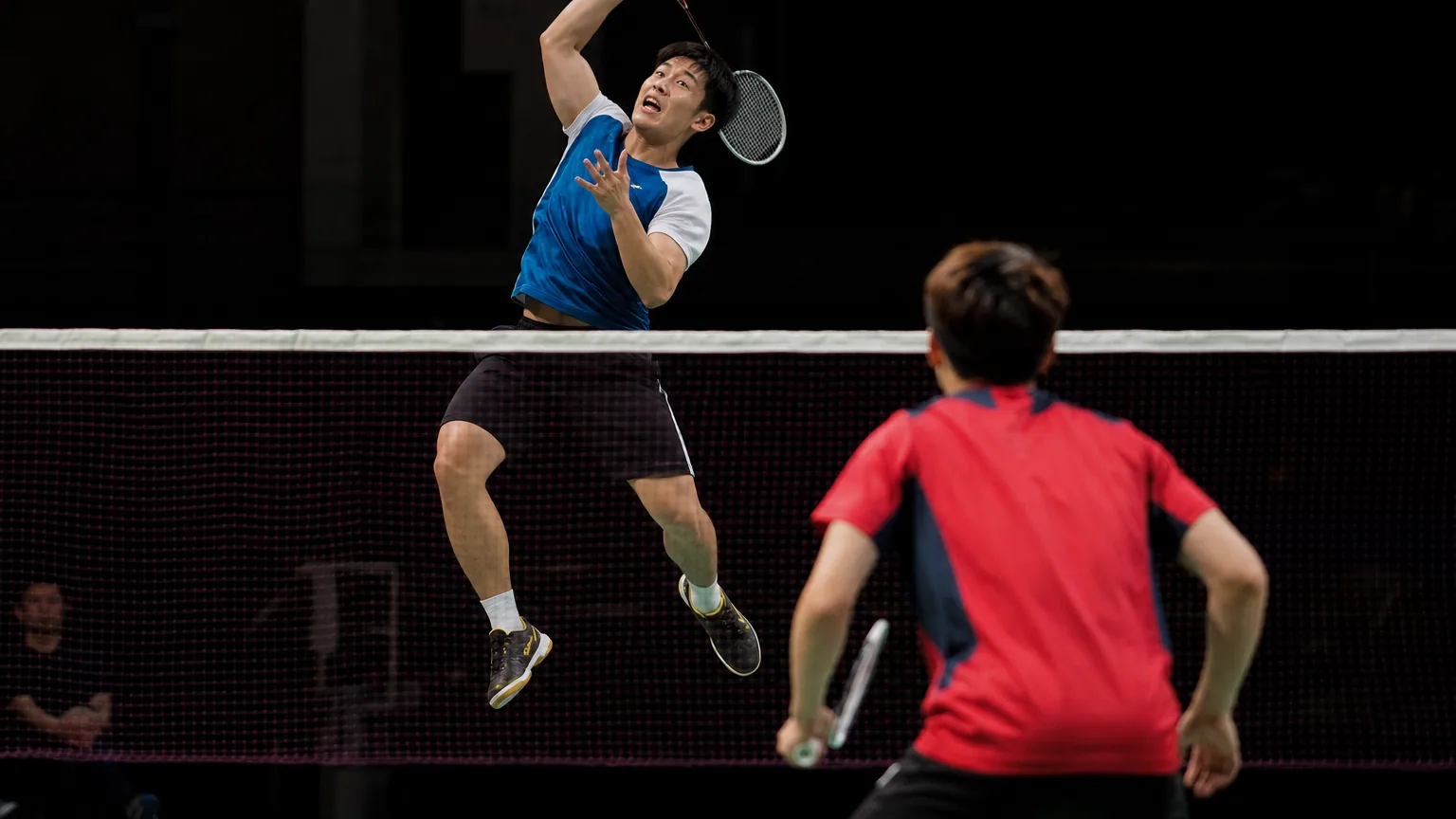 Deux joueurs de badminton s'affrontent sur un terrain en salle