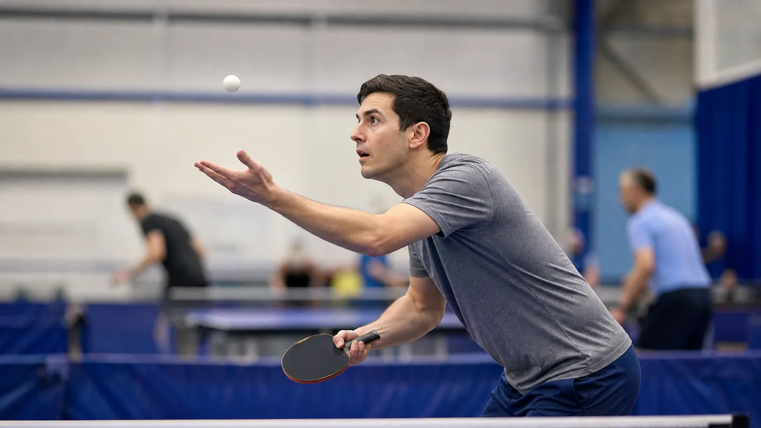 Joueur de tennis de table au service, la balle lancée au-dessus de la main près de la table