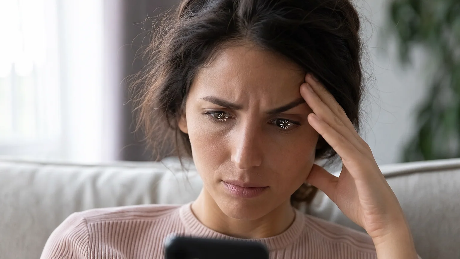 Une femme agacée fixe son smartphone lent en attendant le chargement d'une application