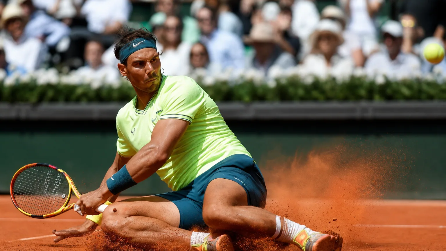 Joueur de tennis glissant sur un court en terre battue, poussière orange autour des chaussures